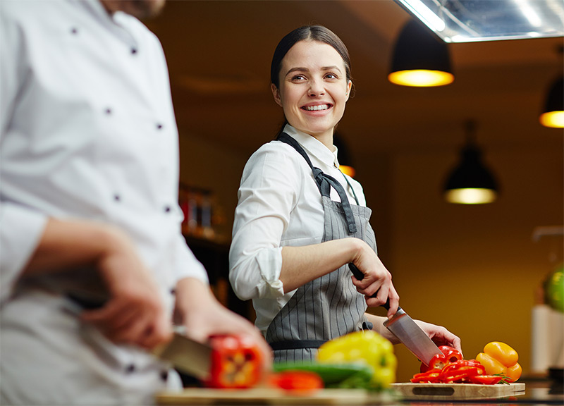 Two chefs chopping peppers